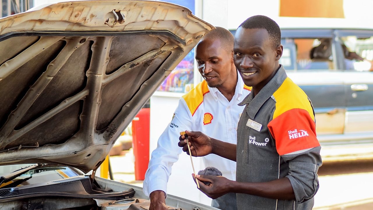engineer pouring Shell lubricant into a car engine